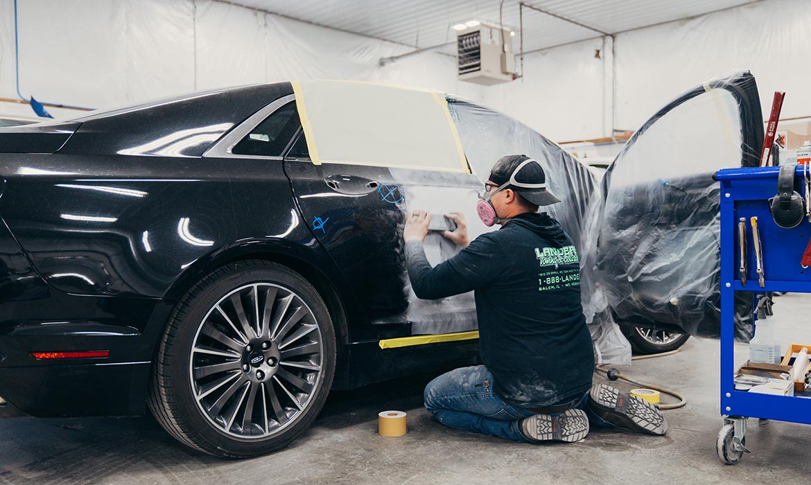 Auto mechanic sanding down door with Landers shirt on
