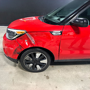 Side of red Kia Sol before collision repair with damaged fender