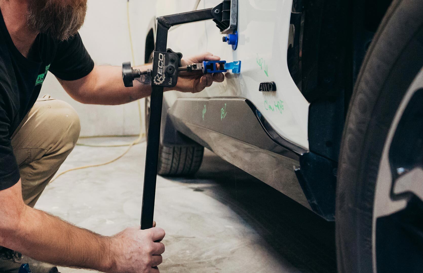 Close up a auto technician pulling a dent of a car