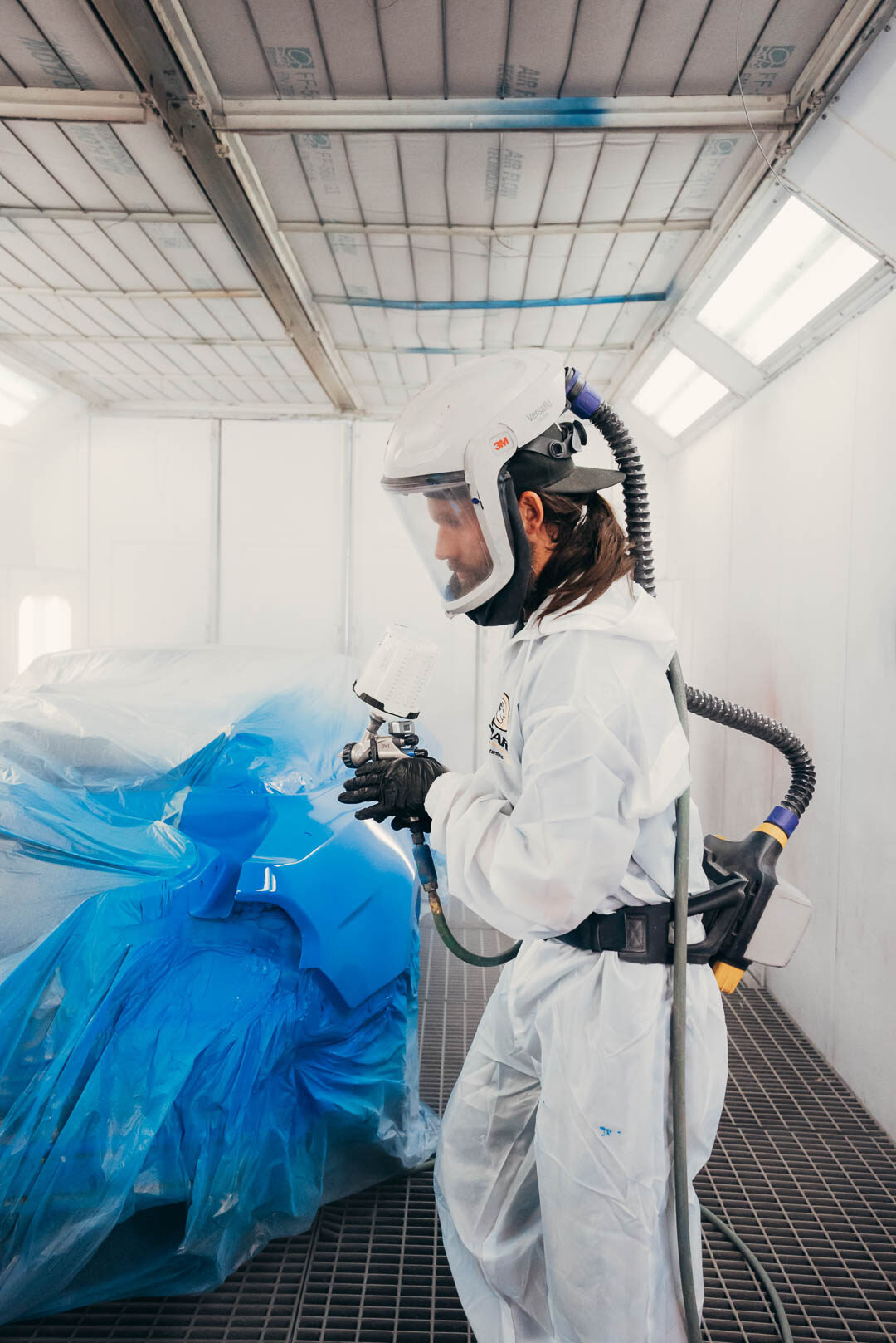 Side profile of Lander's automotive painter suited up preparing for painting