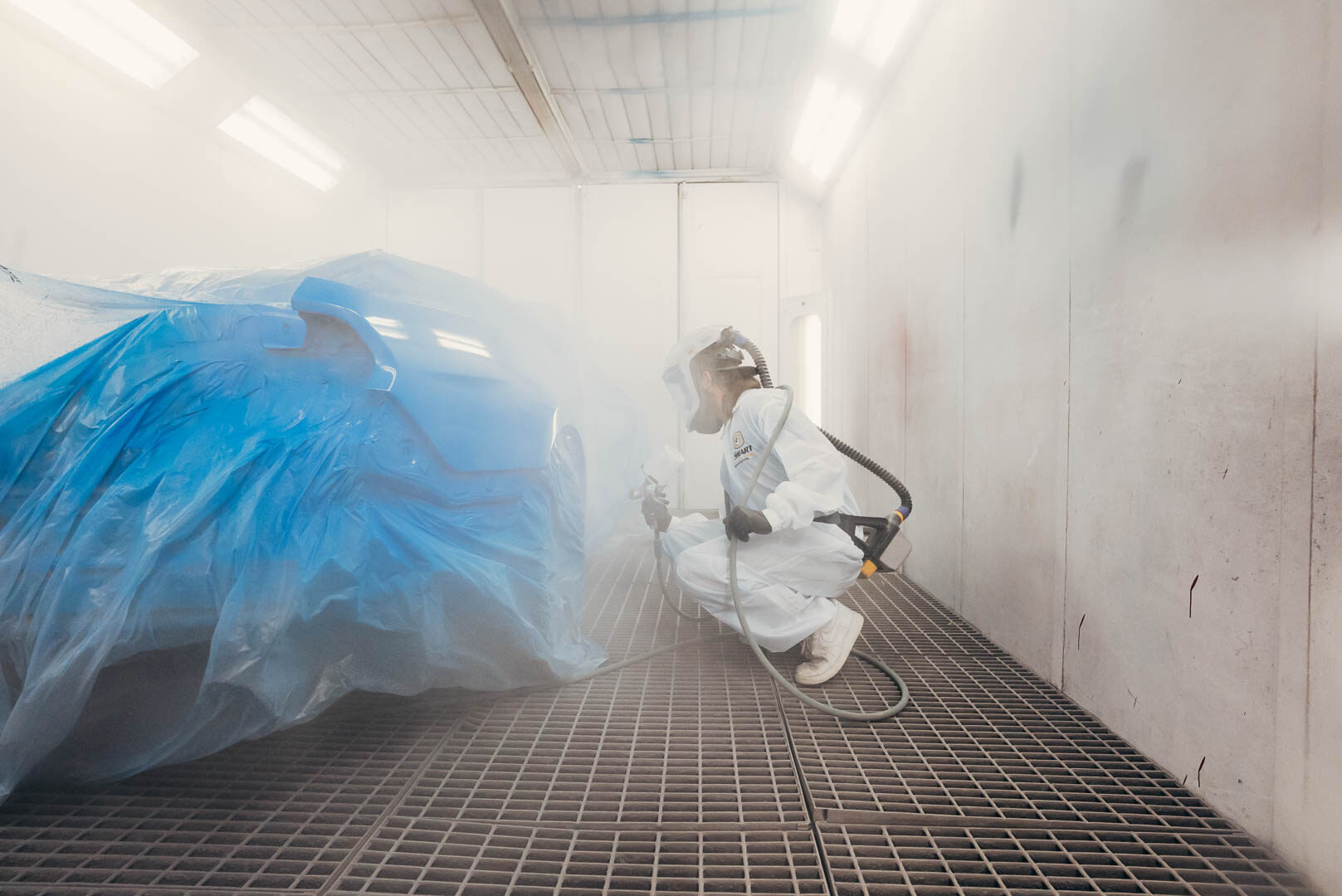 Lander's automotive painter applying paint to vehicle with spray gun with paint mist