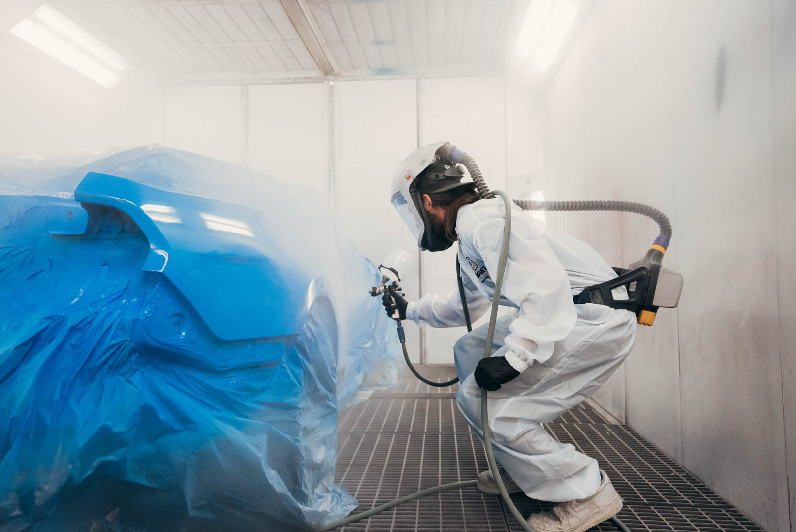 Lander's automotive painter applying paint to vehicle with spray gun