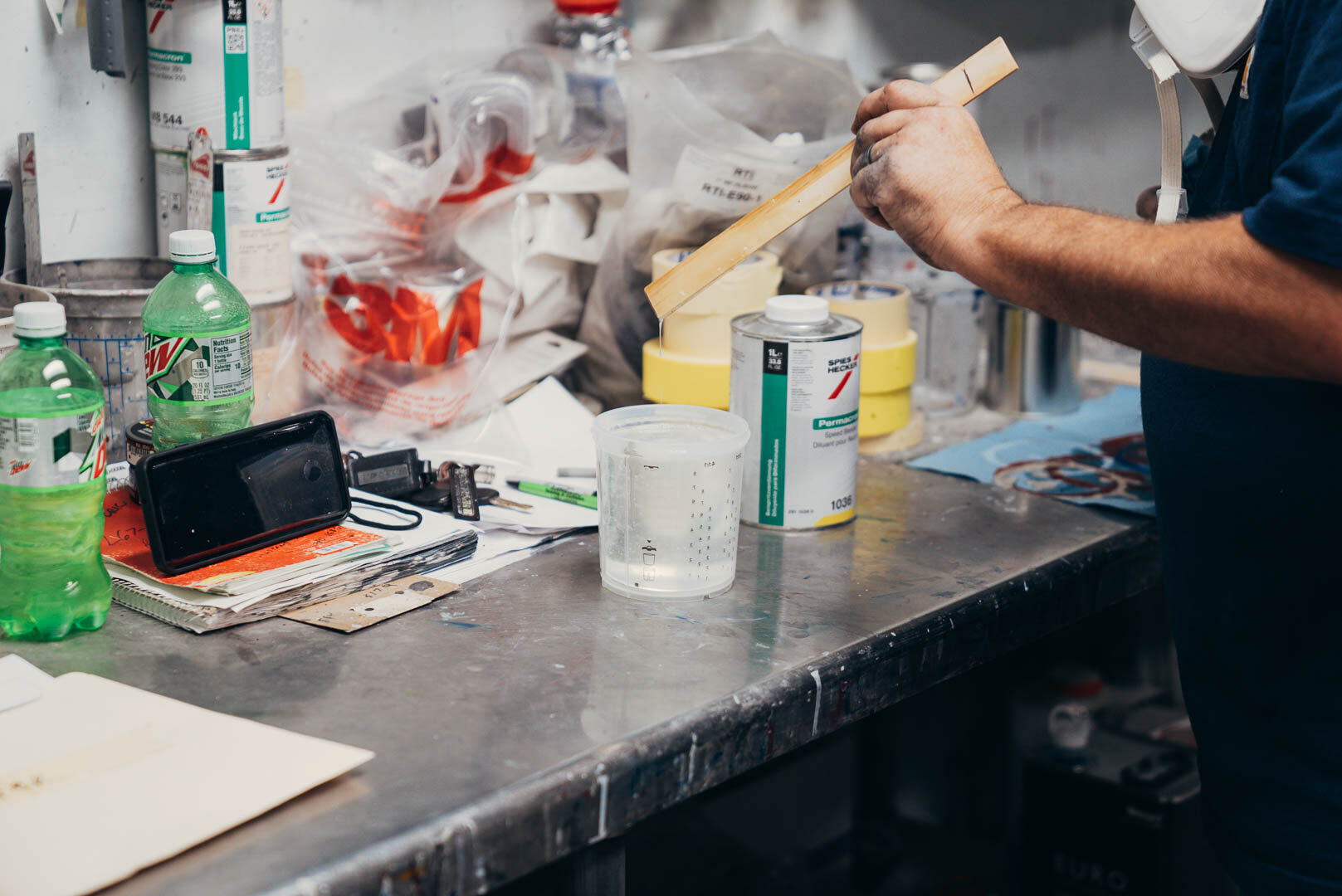 Close up of pulling a mixing stick out of automotive paint