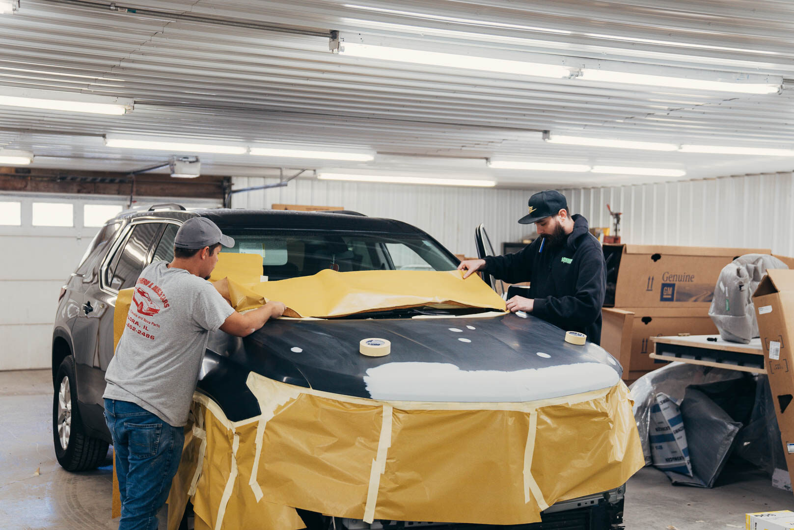 Two Lander's Auto employee's masking out vehicle preparing for body work