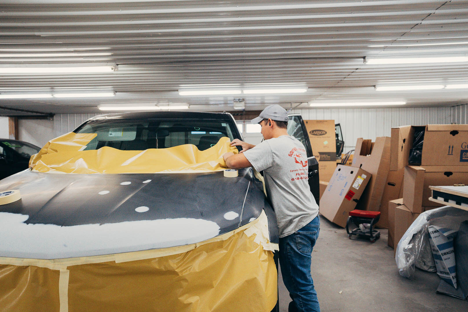Lander's automotive employee is masking out the vehicle, preparing it for work.