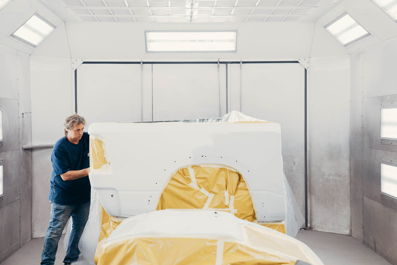 Lander's employee preparing vehicle inside of white painting booth
