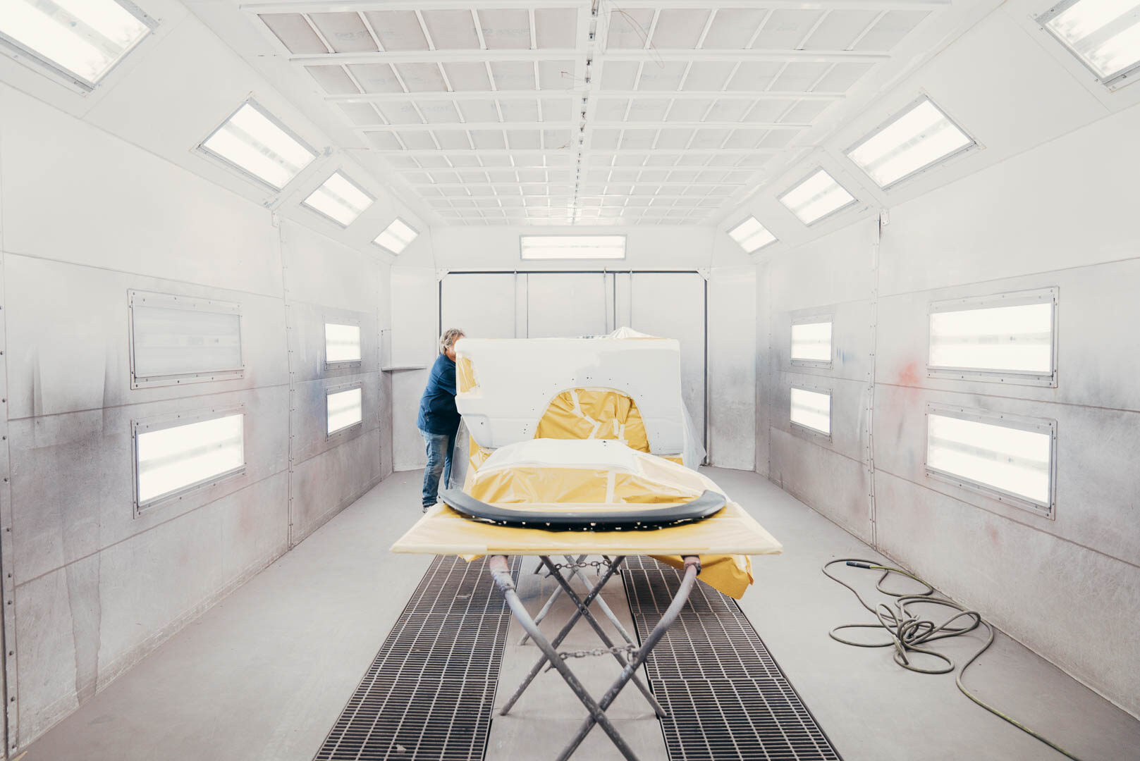 Lander's employee preparing vehicle inside of white painting booth