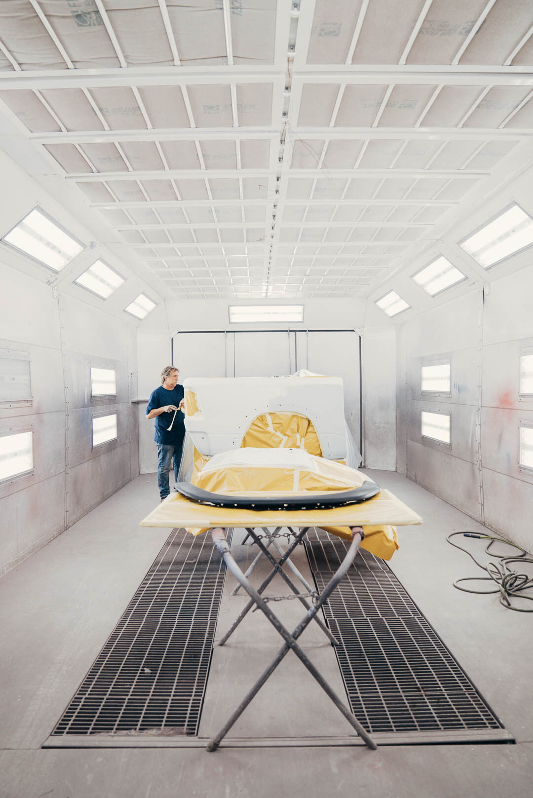 Lander's employee preparing vehicle inside of white painting booth