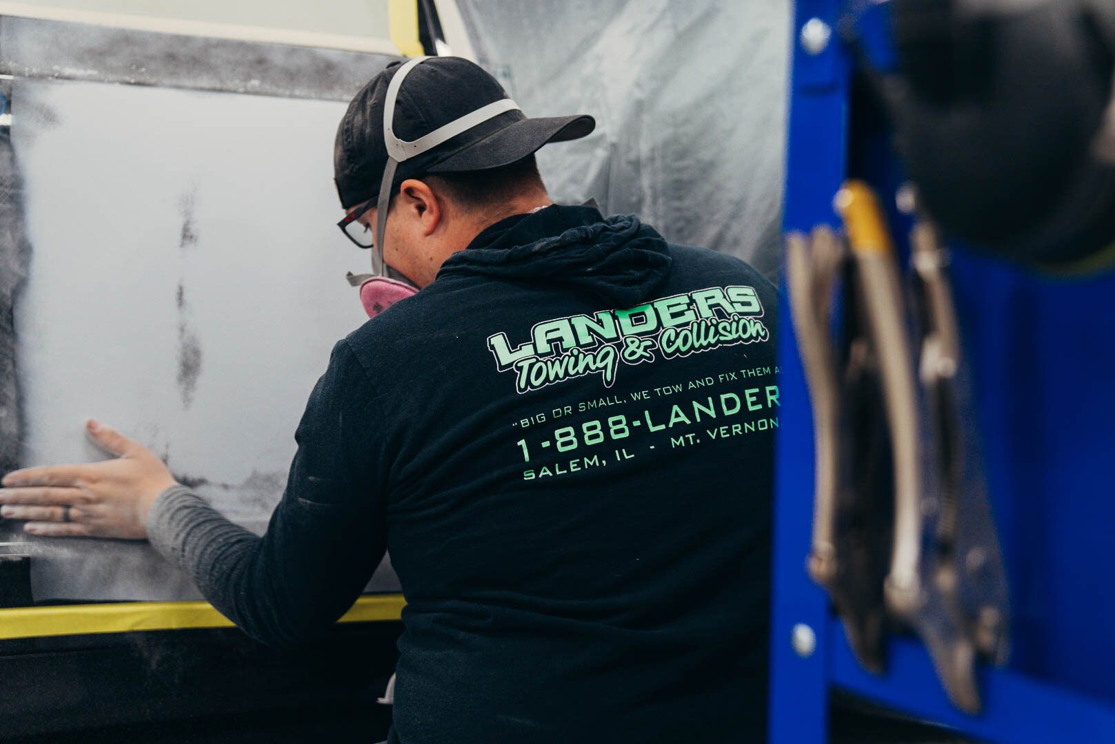 Lander's employee sanding down a vehicle in Lander's T-shirt