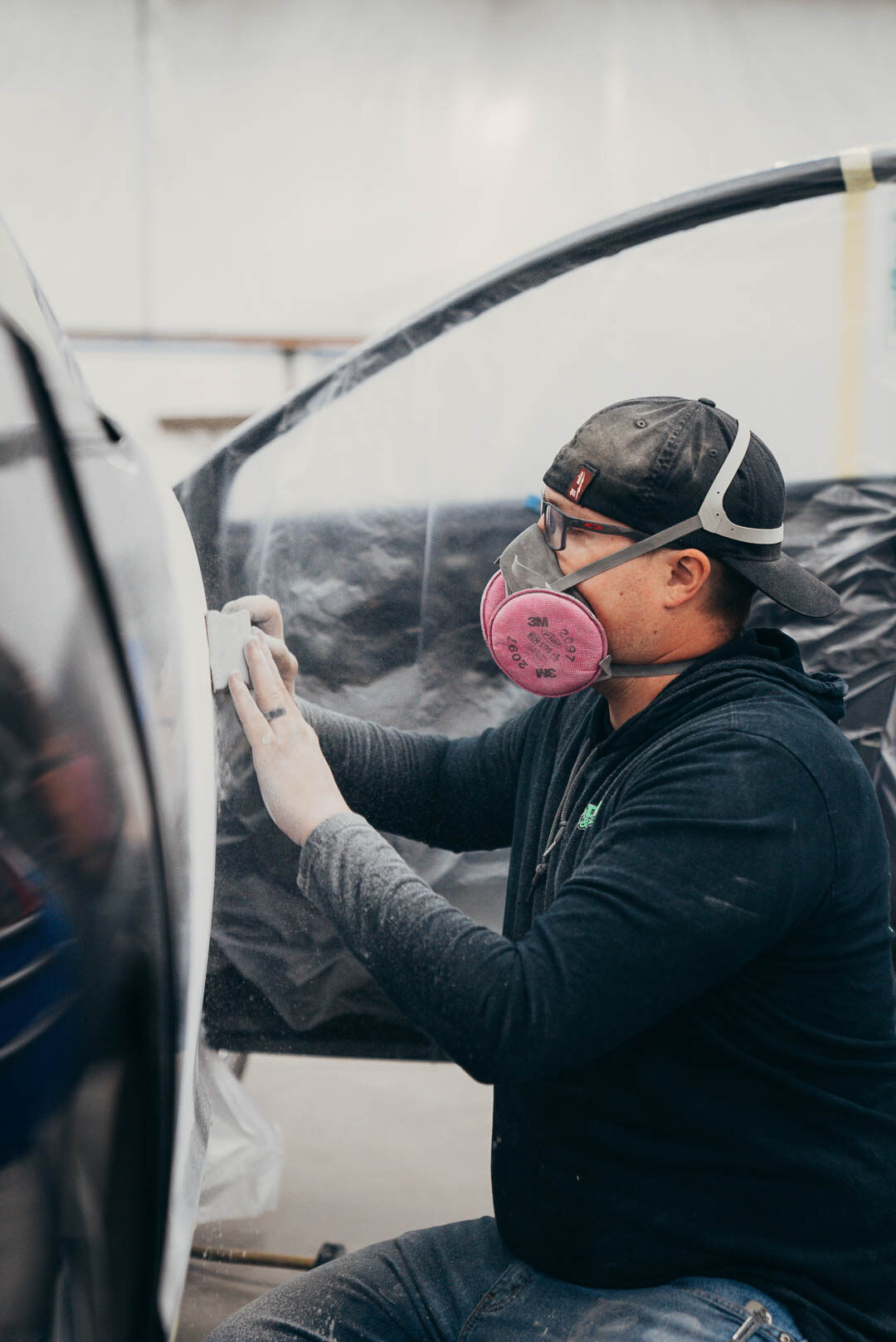 Close-up of Lander's employee sanding down black vehicle