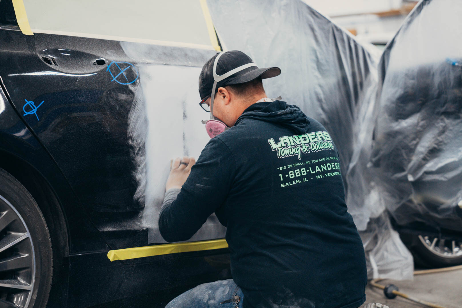 Close-up of Lander's employee sanding down a black car for painting