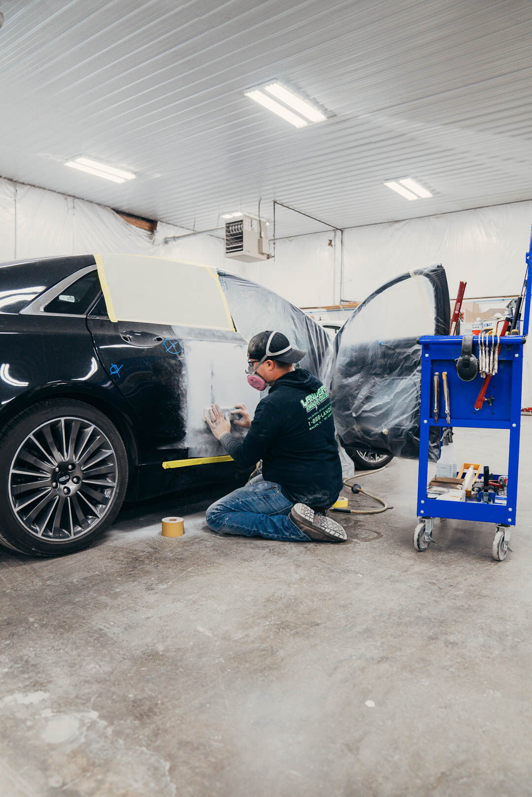 Lander's employee preparing black car for painting