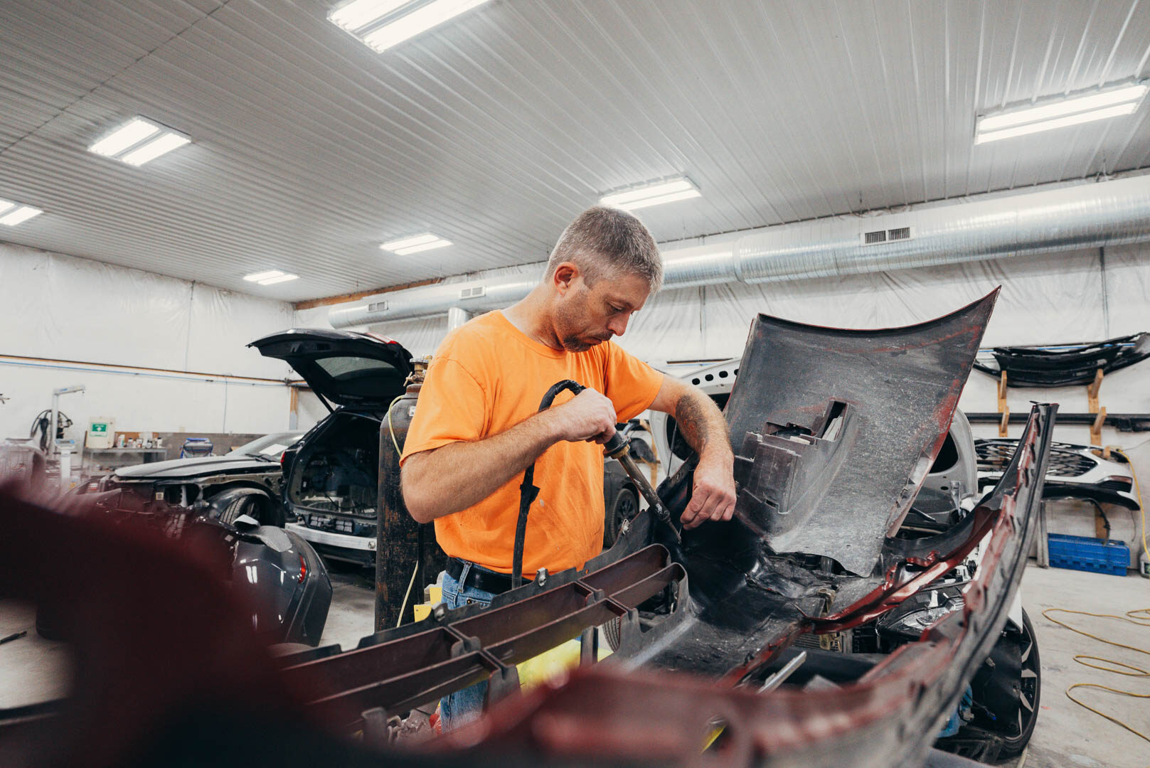 Lander's employee with orange shirt working on vehicle fender