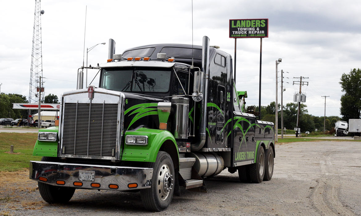Landers heavy-duty towing truck parked in front of sign