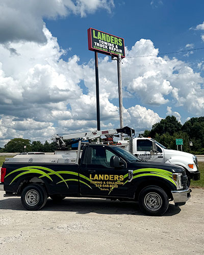 Landers towing trucks parked in front of sign