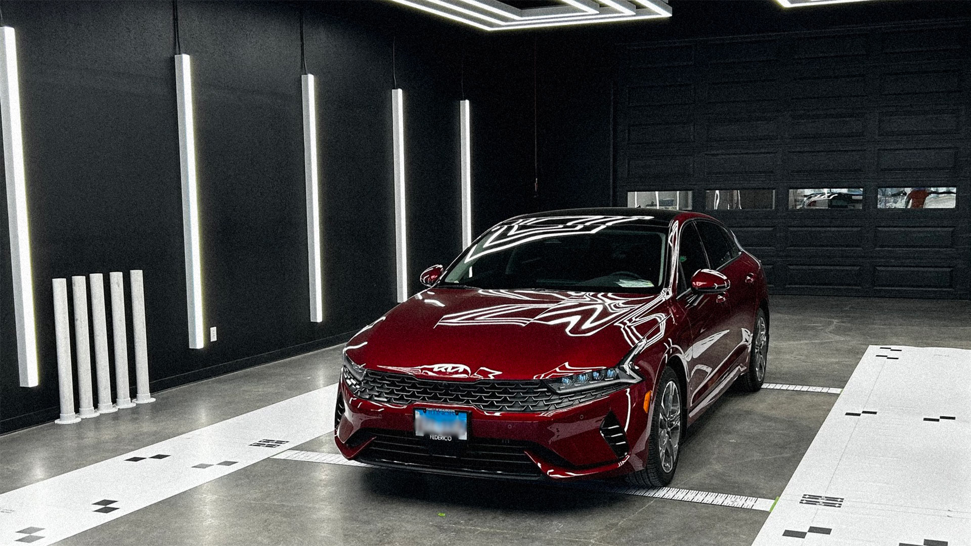 Red Kia sedan in showroom after collision repair